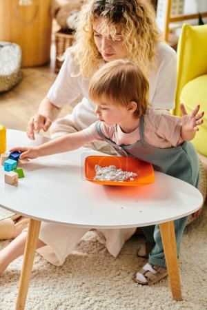 A curly-haired mother engages her toddler daughter in playful learning using the Montessori method at home.