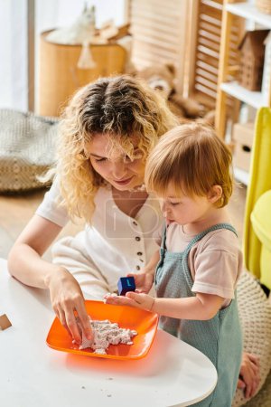 A curly mother and her toddler daughter engage in Montessori learning at a table in a cozy home setting.