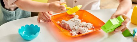 Kleinkind-Mädchen erkundet und spielt mit einem Plastikbehälter voller Lebensmittel in Montessori-inspirierter Lernumgebung zu Hause.
