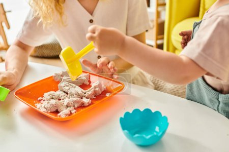 Foto de Un niño pequeño disfruta de una comida en una mesa guiada por su madre, utilizando el método Montessori de educación. - Imagen libre de derechos
