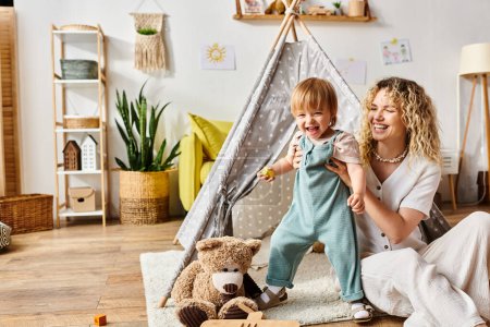 A curly-haired mother and her toddler daughter playfully explore toys in a cozy room