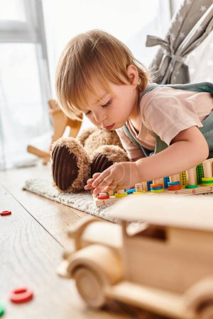 Foto de Una madre rizada observa como su hija pequeña juega felizmente con juguetes en el suelo en casa, inmersa en el método Montessori. - Imagen libre de derechos