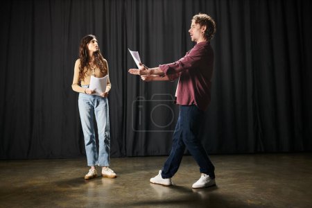 A man and woman discuss a script during theater rehearsals.