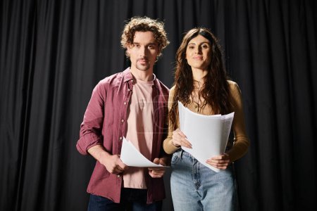 Un hombre guapo está junto a una mujer sosteniendo una hoja de papel durante los ensayos en el teatro..
