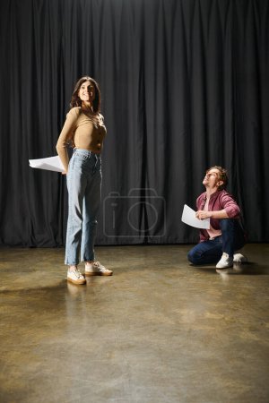 Photo for Woman stands on stage, her partner sits on floor. - Royalty Free Image