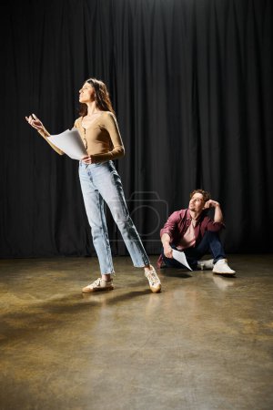 Una mujer y un hombre de pie juntos en un escenario durante los ensayos.