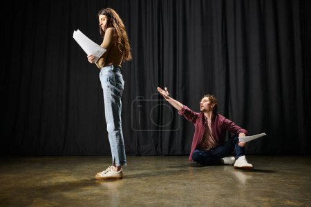 Photo for A man kneels next to a woman on the floor in a theatrical setting. - Royalty Free Image