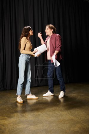 A handsome man and a woman standing together on stage during rehearsals in a theater.