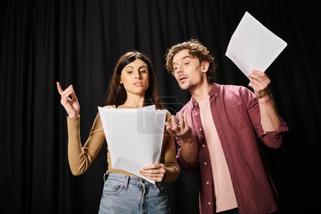 A handsome man and a woman rehearsing together, holding a sheet of paper.
