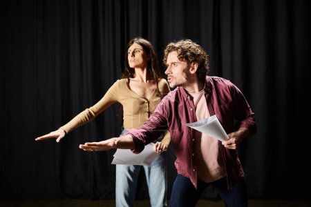 Foto de Un hombre y una mujer de pie juntos con confianza en un escenario de teatro durante los ensayos. - Imagen libre de derechos