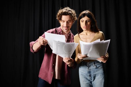 A man and woman stand, studying scripts together.