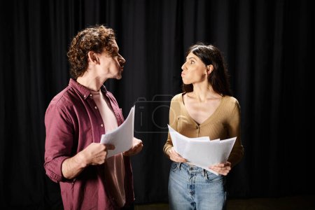 Téléchargez les photos : Un bel homme se tient à côté d'une femme tenant des papiers, répétant pour un spectacle de théâtre. - en image libre de droit