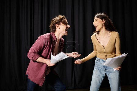 Foto de Un hombre guapo y una mujer de pie juntos en un escenario durante los ensayos. - Imagen libre de derechos