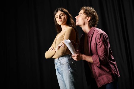 A man and woman strike a pose on stage during theater rehearsals.