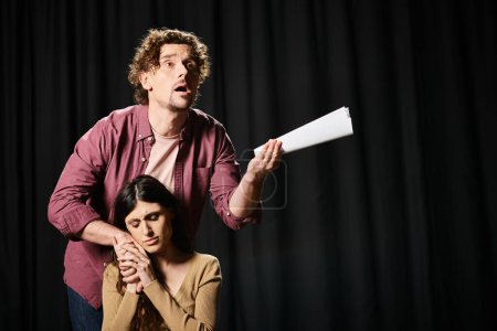 At a theater rehearsal, a handsome man stands next to a woman holding a paper.