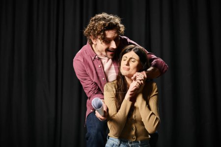 Foto de Un hombre guapo y una hermosa mujer de pie lado a lado, ensayando para una actuación de teatro. - Imagen libre de derechos