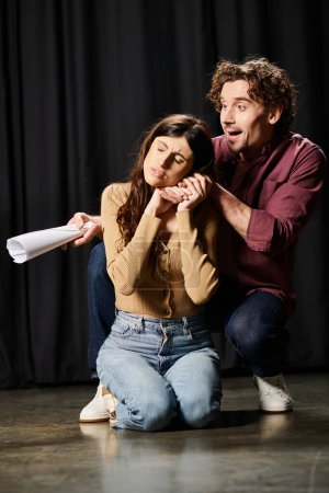 Un hombre se arrodilla junto a una mujer, ensayando para una actuación de teatro.