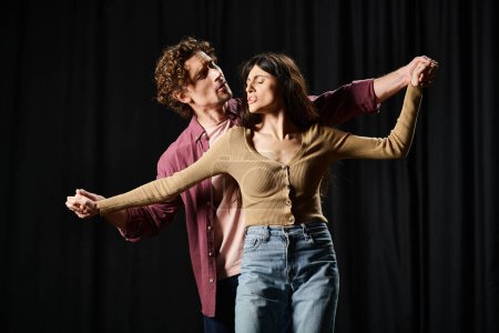 A man and a woman gracefully dance together in a theater rehearsal.