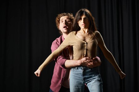 A man lovingly holds a woman in his arms during a theater rehearsal.