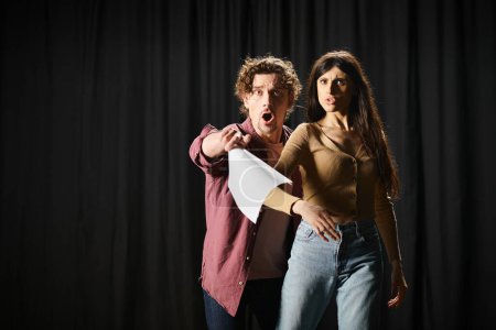 Foto de Un hombre y una mujer con estilo posan con confianza frente a una cortina negra durante los ensayos de teatro. - Imagen libre de derechos