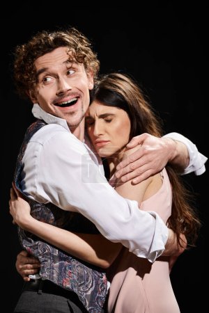 Un hombre guapo y una mujer hermosa abrazándose apasionadamente durante un ensayo de teatro.