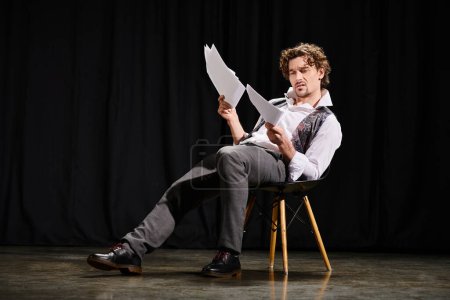 A man engrossed in reading a script while seated in a chair.