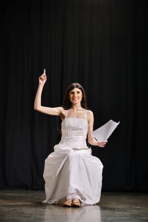 Femme élégante en robe blanche s'assoit gracieusement sur scène pendant les répétitions.