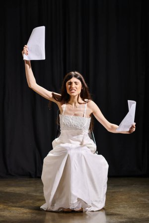 Woman in white dress holds script.