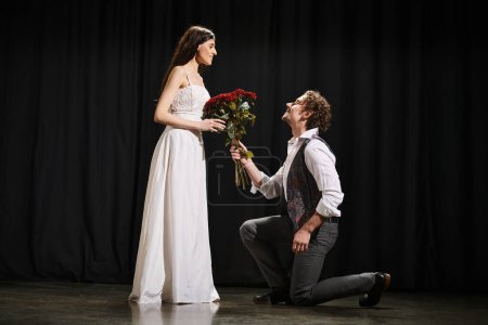 Un hombre se arrodilla junto a una mujer sosteniendo flores durante un ensayo de teatro.