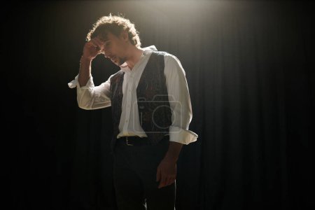 Photo for A man in a vest and tie stands confidently in a dimly lit room. - Royalty Free Image