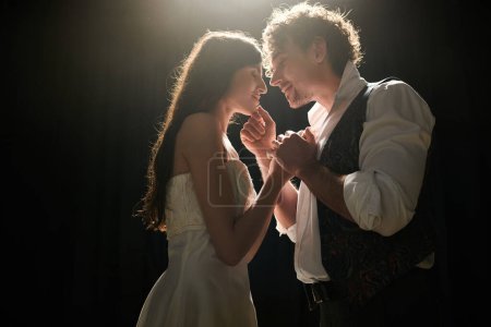 Elegant man and woman gracefully dance together in low light setting.