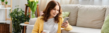 Photo for Middle aged woman sits on couch, engrossed in cellphone. - Royalty Free Image