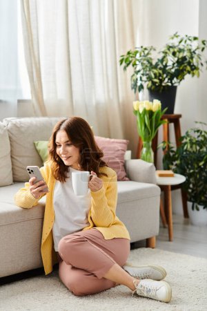 Middle-aged woman sits on floor, savoring a cup of coffee.