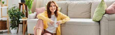 Photo for Middle-aged woman lounging on couch, holding coffee cup. - Royalty Free Image