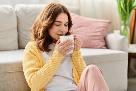 Frau mittleren Alters genießt einen Moment mit Kaffee auf einer gemütlichen Couch.