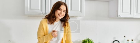 Mujer de mediana edad en cárdigan amarillo de pie con gracia en la cocina.