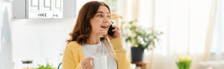 Téléchargez les photos : Une femme d'âge moyen élégante parle sur son téléphone portable tout en tenant une tasse de café. - en image libre de droit