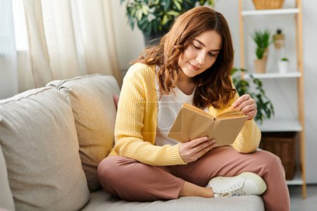 Middle aged woman peacefully engrossed in reading while seated on a sofa.
