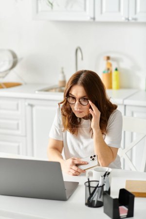 Téléchargez les photos : Femme d'âge moyen engagée dans le travail d'ordinateur portable à la table. - en image libre de droit