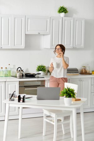 Middle-aged woman conversing on cell phone in home kitchen.