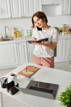 Foto de Mujer de mediana edad de pie en una cocina sosteniendo un libro. - Imagen libre de derechos