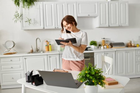 Middle-aged woman absorbed in reading book while standing in kitchen.