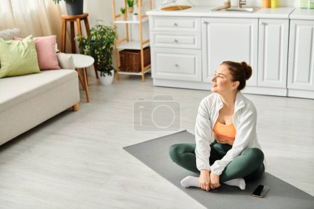 Middle aged woman exercises yoga on mat in living room.