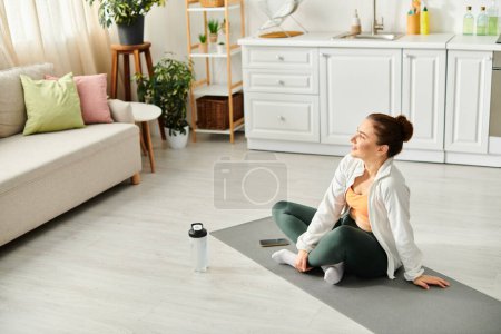 A middle-aged woman finds peace while sitting on a yoga mat in her living room.
