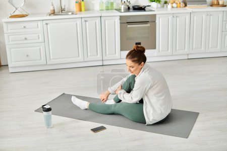 Femme d'âge moyen trouver la paix intérieure sur un tapis de yoga dans sa cuisine.