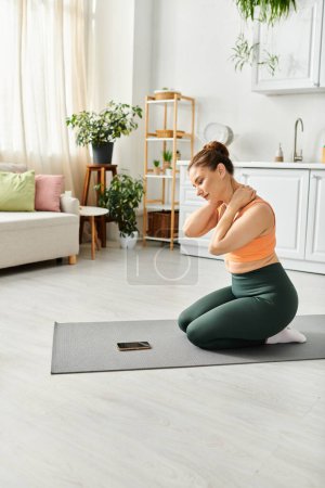 Foto de Mujer de mediana edad practicando pacíficamente yoga en una alfombra acogedora en su sala de estar en casa. - Imagen libre de derechos