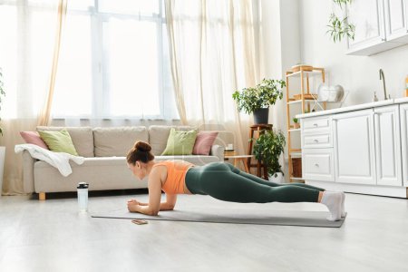 Mujer de mediana edad practicando con gracia yoga en su casa.