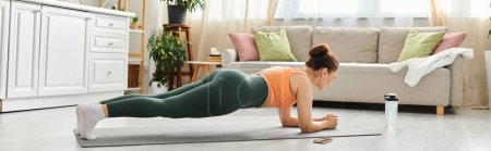 Photo for Middle-aged woman performing a plank on a yoga mat at home. - Royalty Free Image
