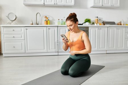 Frau mittleren Alters auf Yogamatte checkt Smartphone.