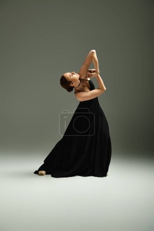 Foto de Joven hermosa bailarina en un vestido negro golpea una pose de baile. - Imagen libre de derechos